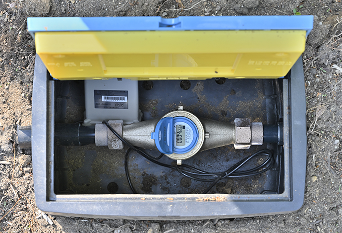 アズビル金門の電子式水道メーターと無線通信端末。水道メーターの交換のタイミングで無線通信端末を取り付け、ボックス内に収納している。